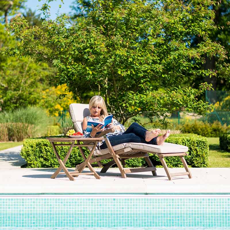 Woman relaxing on Steamer Chair by Swimming Pool