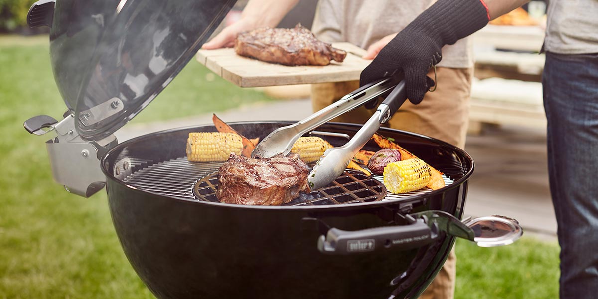 Man cooking food on a Weber Charcoal BBQ