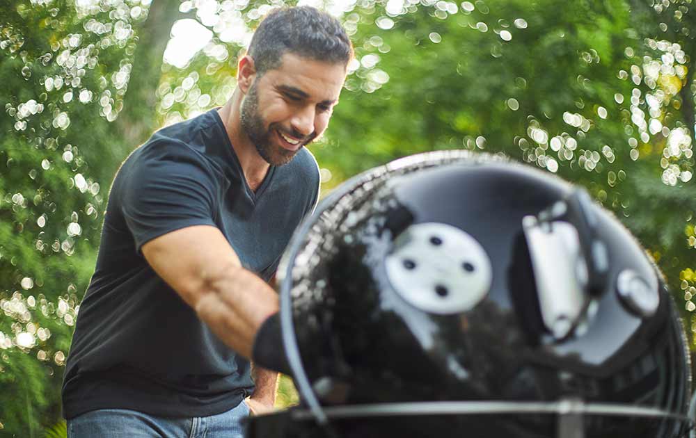 Man cooking on BBQ with Lid Up