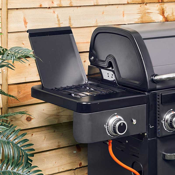 Black Grillstream BBQ with open lid showing side burneragainst a wooden fence background