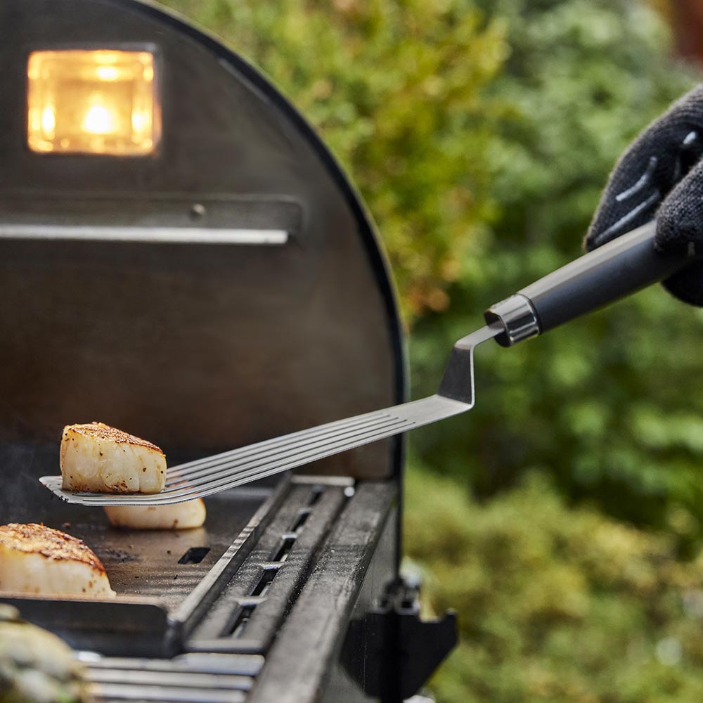 Weber Flexible Griddle Spatula in use lifting scallops from the griddle