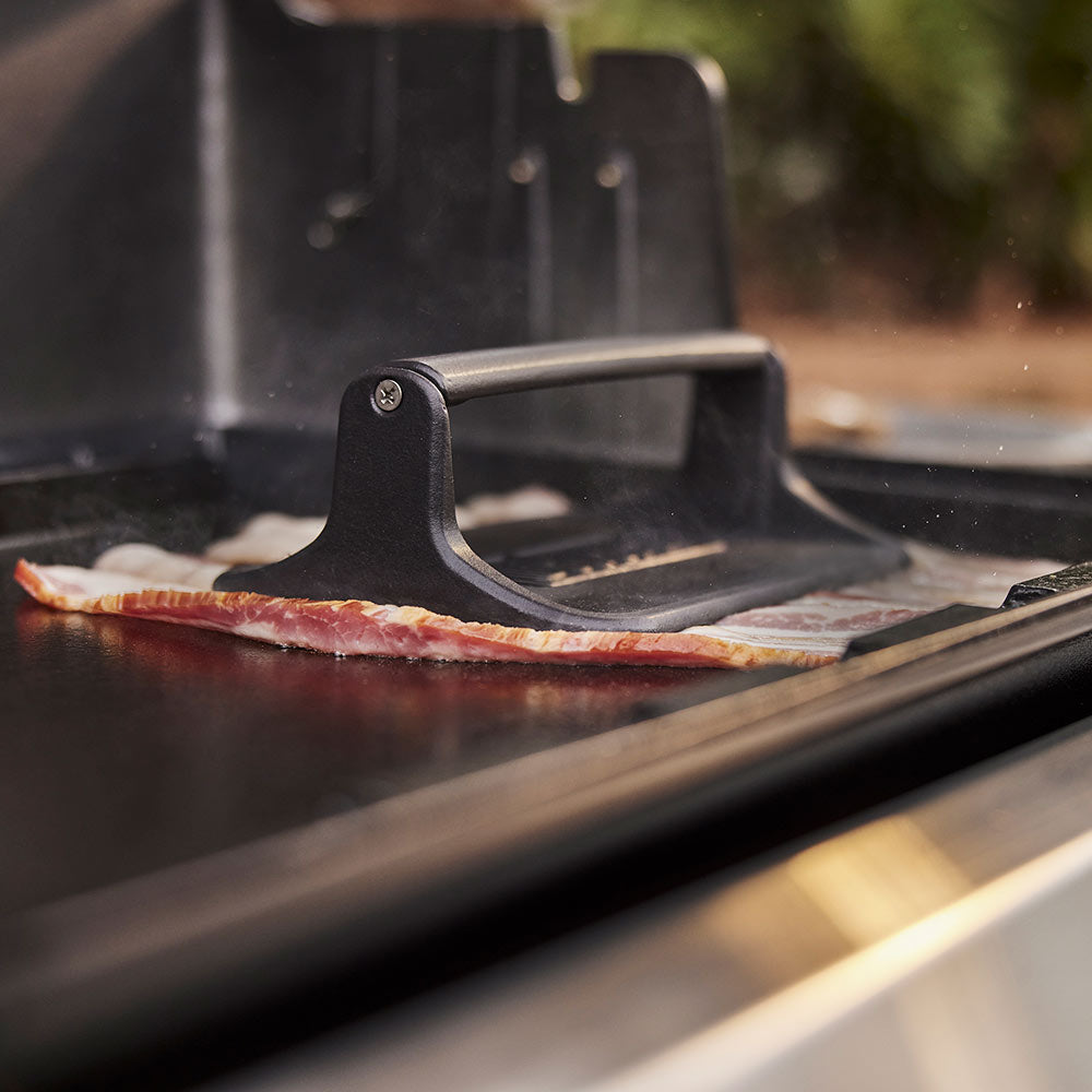 Weber Griddle Press in use, smashing a burger on the griddle