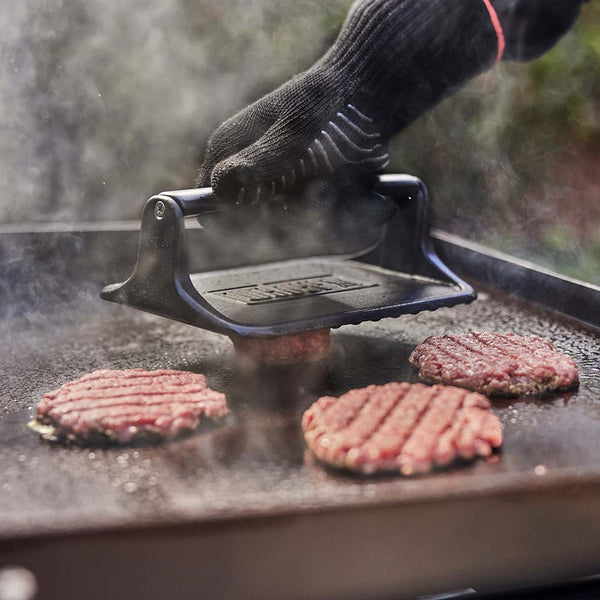 Weber Griddle Press in use making a patty on the griddle