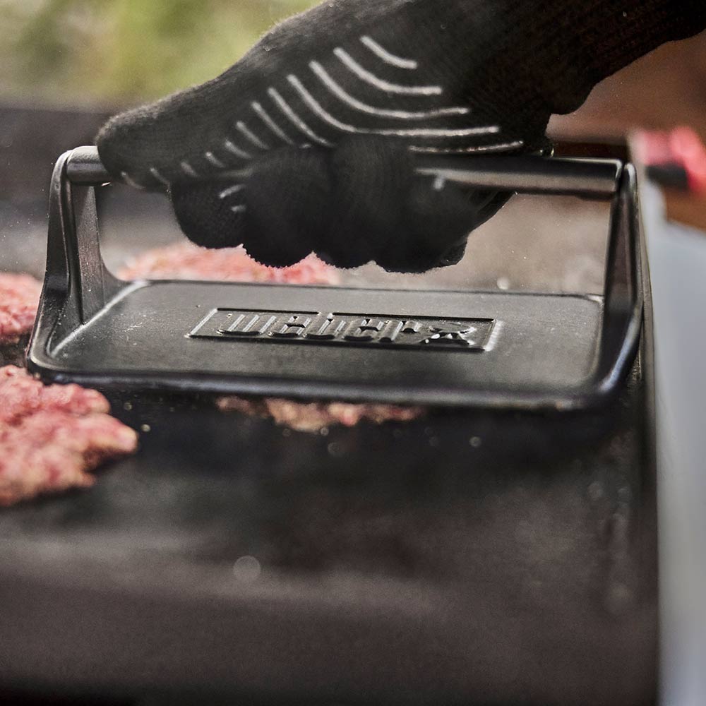 Weber Griddle Press in use, smashing a burger on the griddle