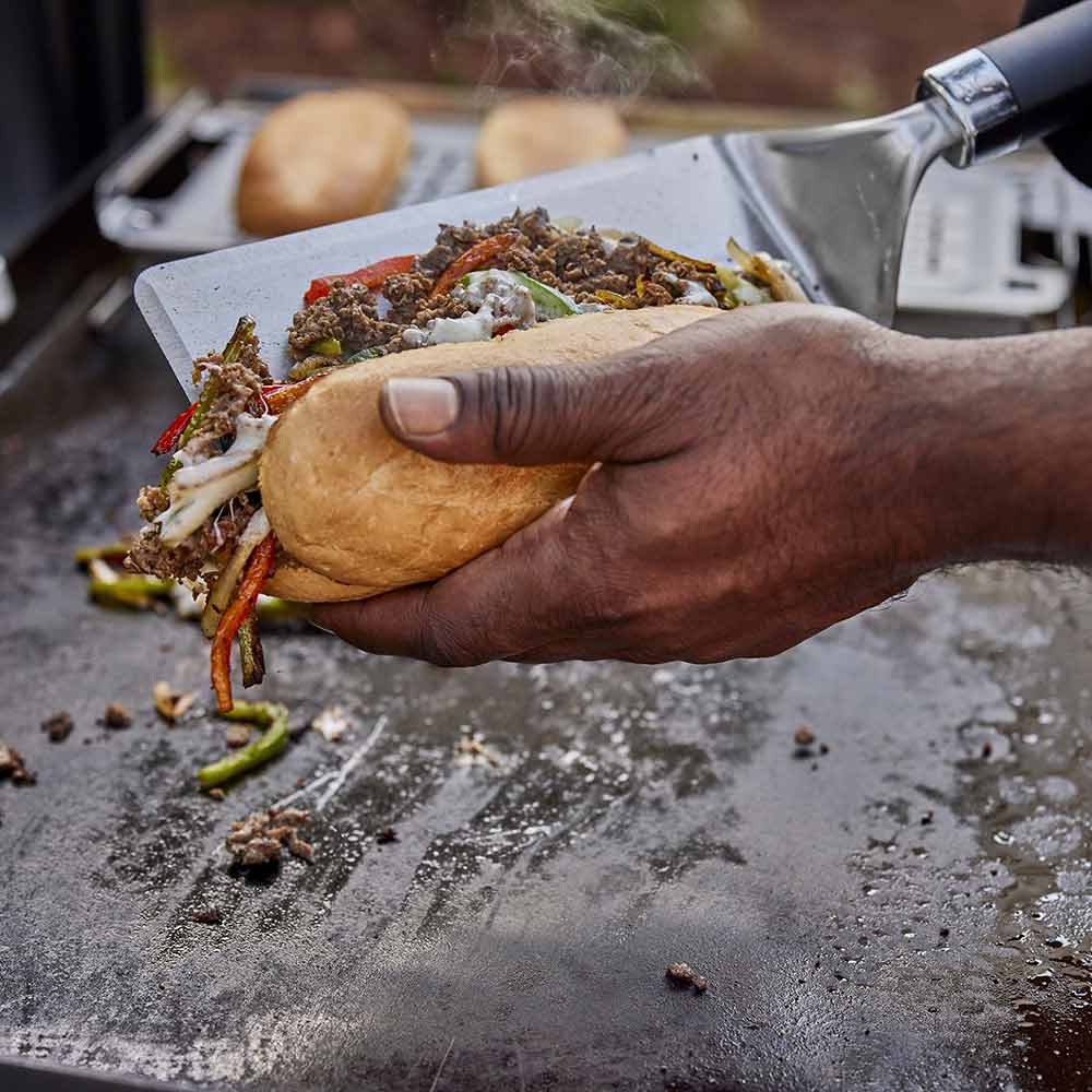 Weber Griddle Spatula in use loading fajitas into bun
