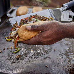 Weber Griddle Spatula in use loading fajitas into bun