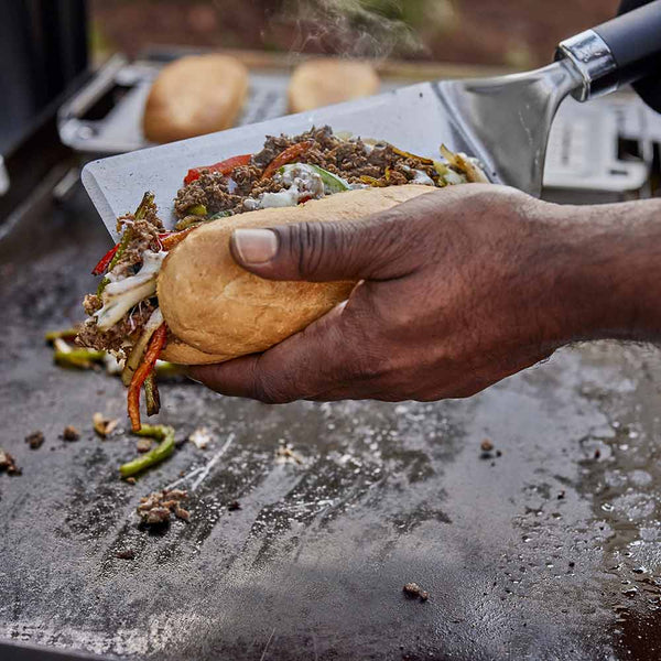 Weber Griddle Spatula in use loading fajitas into bun