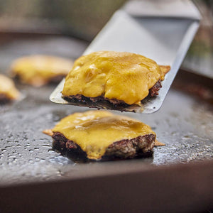 Weber Griddle Spatula in use lifting cheeseburgers