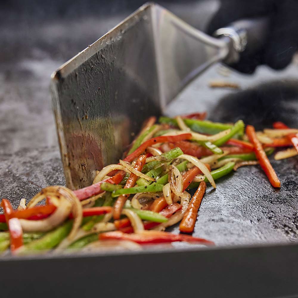 Weber Griddle Spatula in use loading fajitas into bun