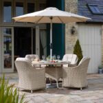 Bramblecrest Monterey 4 Seater Dining Set in Sandstone with Parasol & Base on patio