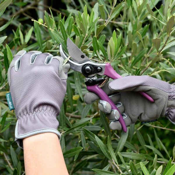 Hands wearing the limited edition grey Burgon & Ball Gardening Gloves to prune plants.