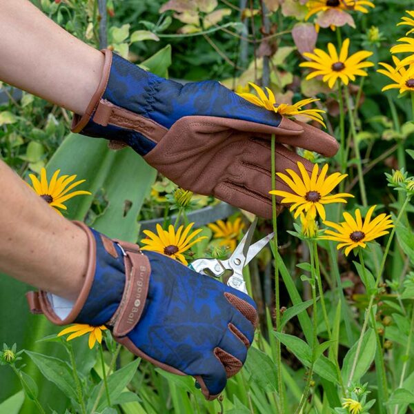 Hands wearing the Navy Oak Leaf Burgon & Ball Gardening Gloves to prune plants.