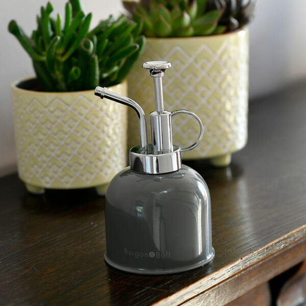 A Burgon & Ball Indoor Plant Mister in charcoal grey sat on a wooden shelf.