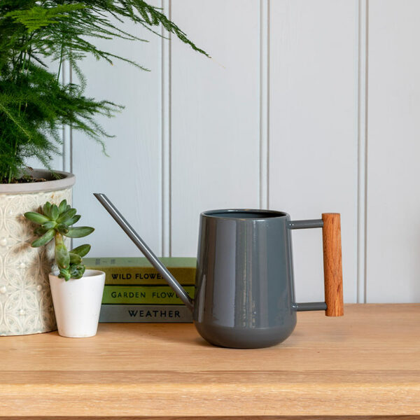 The Burgon & Ball Indoor Watering Can in charcoal grey, sat on a wooden shelf.