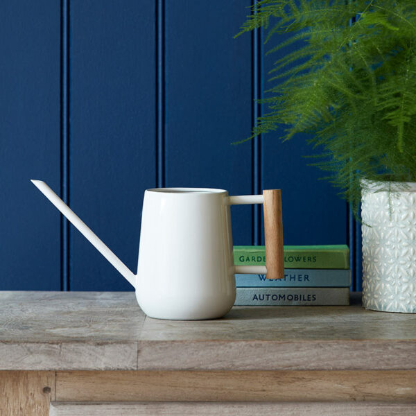 The Burgon & Ball Indoor Watering Can in a stone colour, sat on a wooden table.