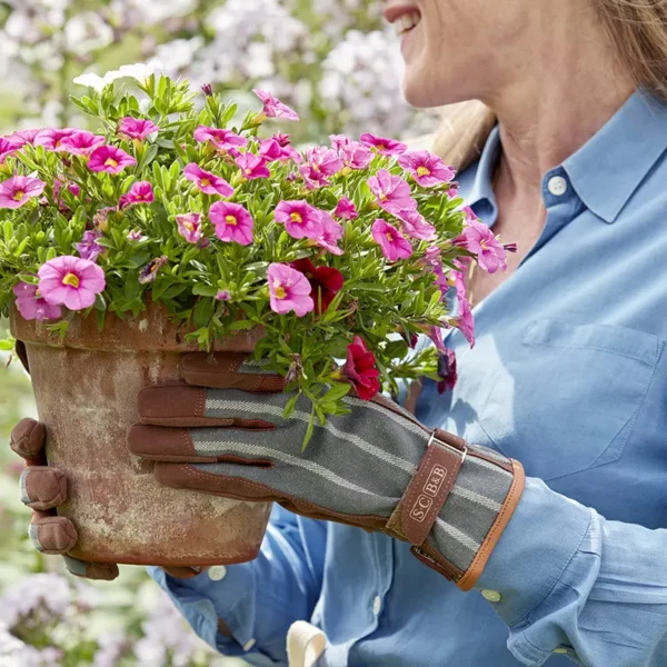 Sophie Conran wearing the Burgon & Ball Sophie Conran Everyday Gloves in grey to carry a plant pot.