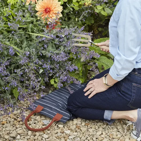 Sophie Conran kneeling on the edge of the navy and white Burgon and Ball Sophie Conran Garden Kneeler.