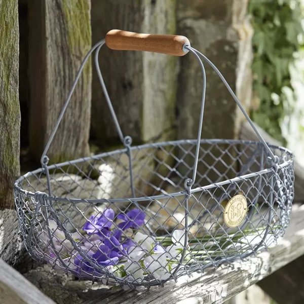 A Burgon & Ball Sophie Conran Large Harvest Basket sat outside holding flowers.