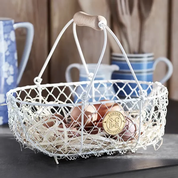 A Burgon & Ball Sophie Conran Small Harvest Basket sat on a counter holding eggs.