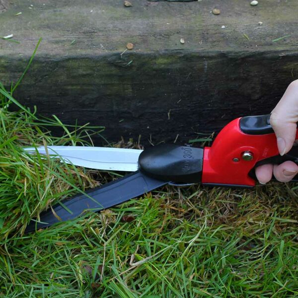 A pair of Darlac Swivel Shears with angled blades cutting through grass against a garden border edging.