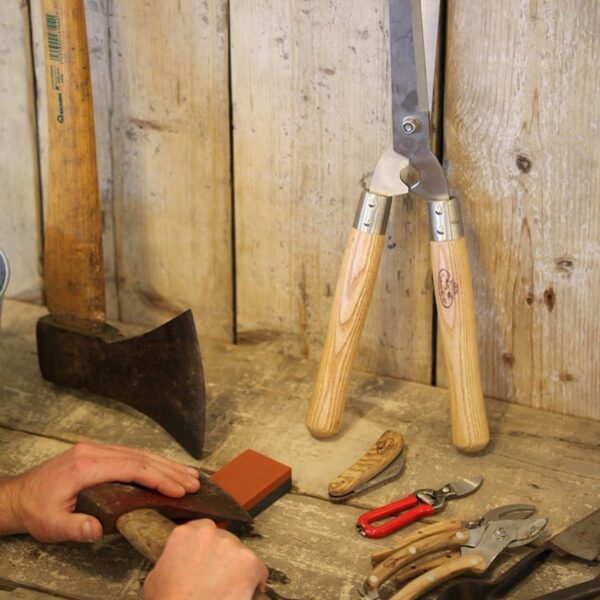 An axe being sharpened on the orange, 180 grit side of the Fallen Fruits Gardening Whetstone.