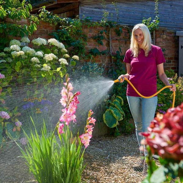 A woman spraying the Hozelock Wonderhoze into a flower bed.