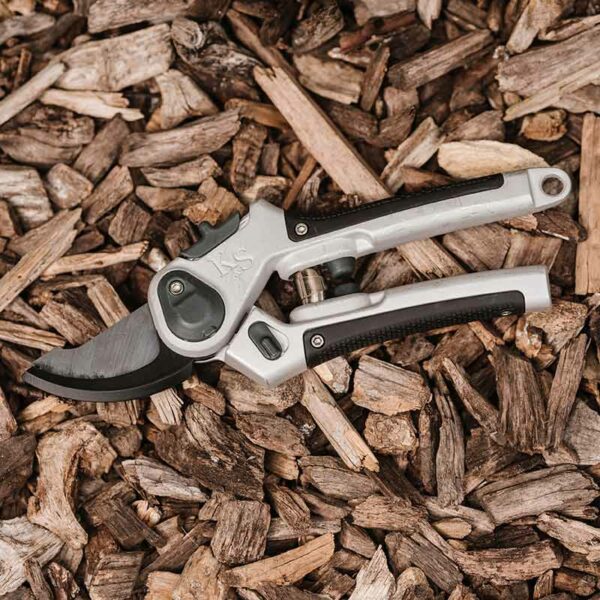 A pair of Kent & Stowe Eversharp All Purpose Lite Secateurs lying in bark. The secateurs have black rubber handles and dark carbon blades.