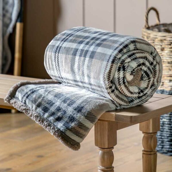 Tartan Sherpa Throw in Natural colours rolled up and displayed on wooden table