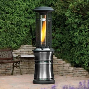 The Lifestyle Santarini Gas Patio Heater with the flame glowing on a Garden Patio with a wooden bench and a green bush in the background
