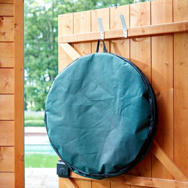 A collapsed Jumbo Pop-Up Garden Waste Spring Bin hung on a hook on the back of a wooden shed door.