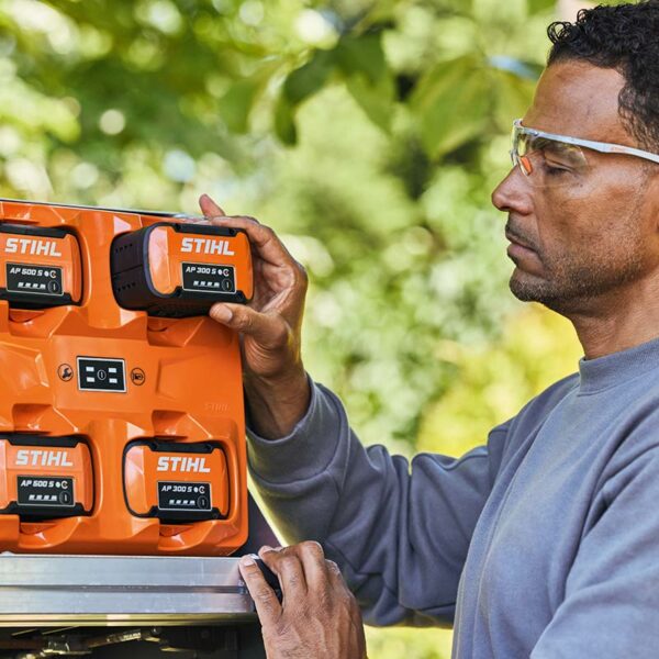 A man pushing the STIHL AP 300 S Battery into a charging slot.