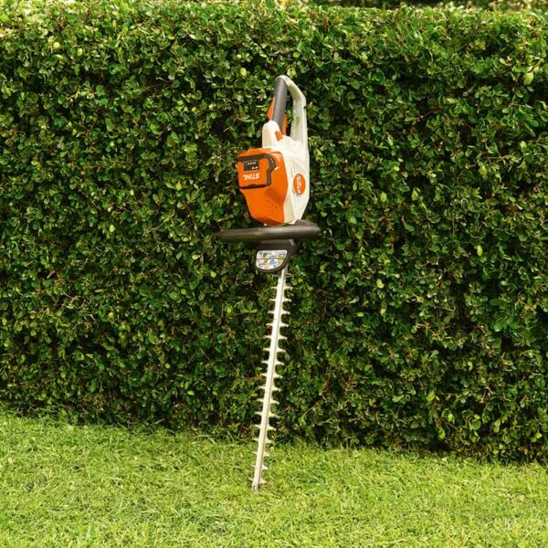 The STIHL HSA 50 Cordless Hedge Trimmer leant against a flat trimmed hedge.