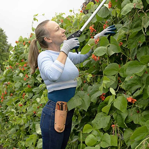 A woman using a pair of grey Town & Country ECO-Flex Comfort Gloves to prune a hedge.