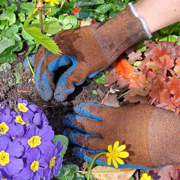 A pair of hands wearing the Town & Country ECO-Flex Pro Gloves to pull put weeds.