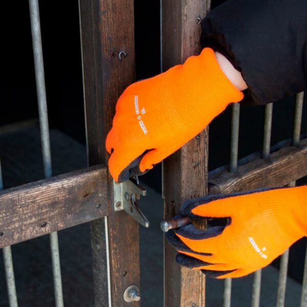Someone operating a door latch while wearing the bright orange Town & Country MasterGRIP Thermolite Gloves.