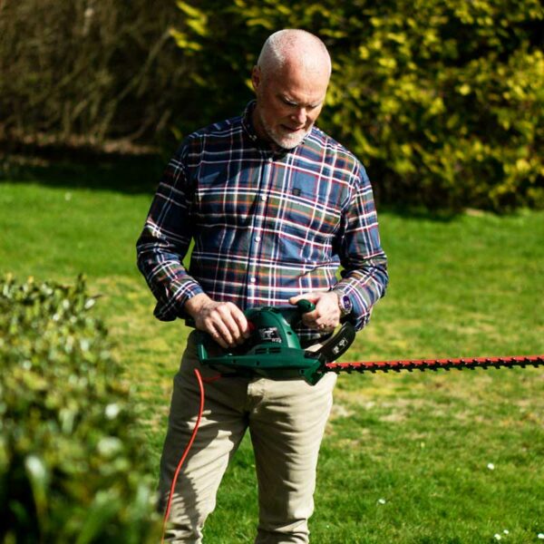 A man holding the Webb Classic 500W 51cm (20") Hedge Trimmer.