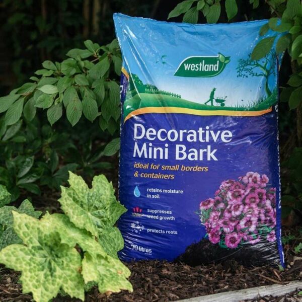 A 70 litre compost bag of Westland Decorative Mini Bark sat on a flower bed.