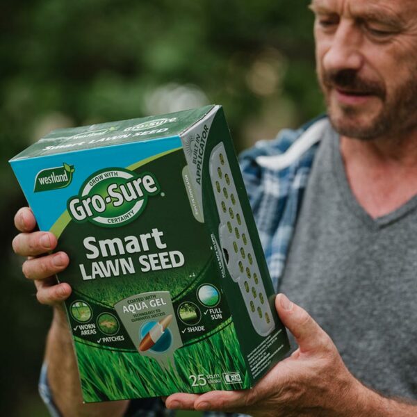 A man inspecting the back of the 1kg cardboard carton of Westland Gro-Sure Smart Lawn Seed.