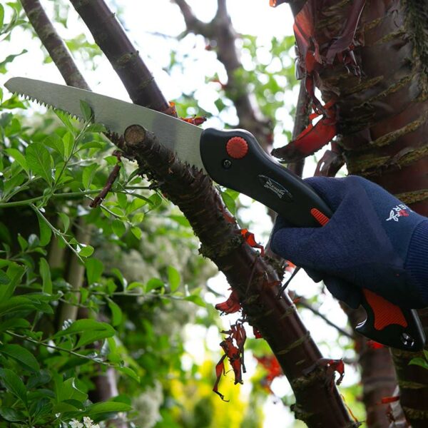 A hand cutting a branch with the Wilkinson Sword Folding Saw.