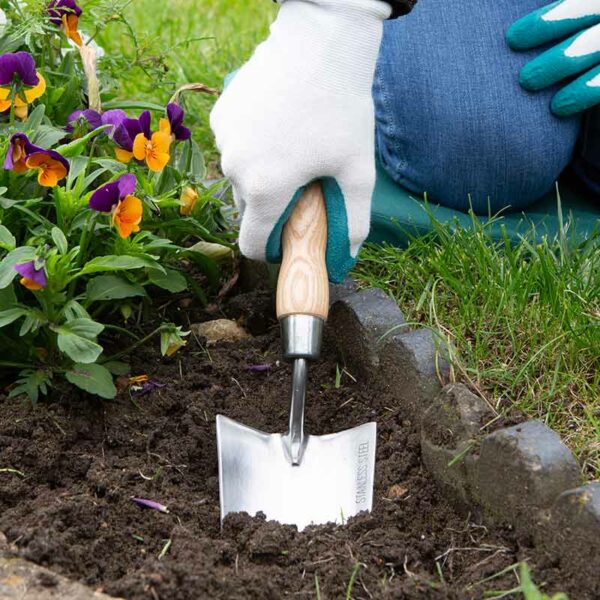 A Wilkinson Sword Stainless Steel Hand Trowel digging into the soil.