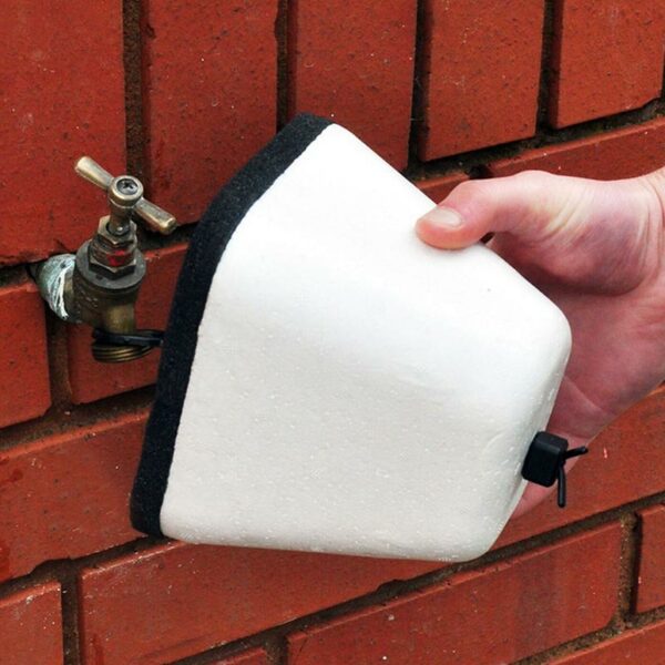 A white Winter Protection Anti-Freeze Tap Cover mounted on a brick wall.